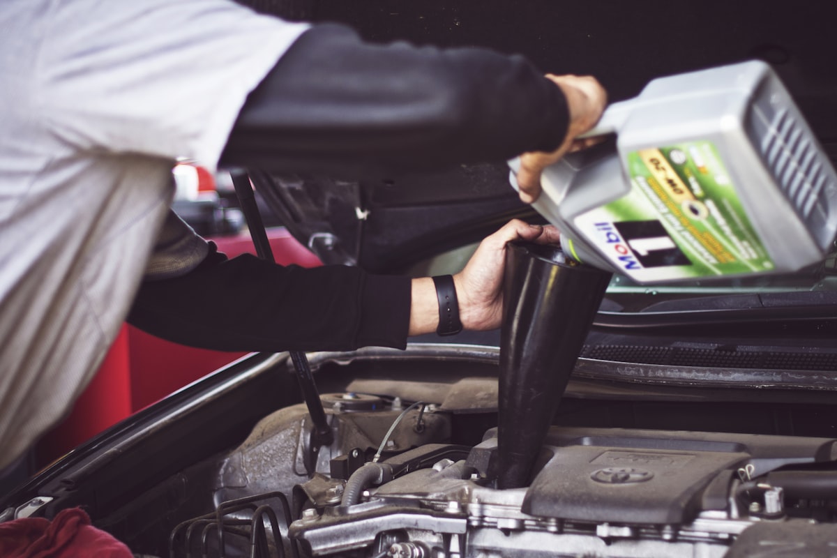 Technician pouring fresh oil into a car engine